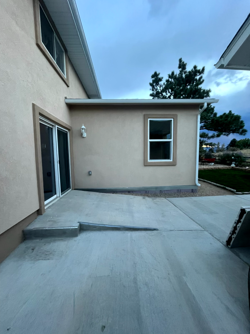 Exterior view of a beige building with a concrete patio and a small ramp.