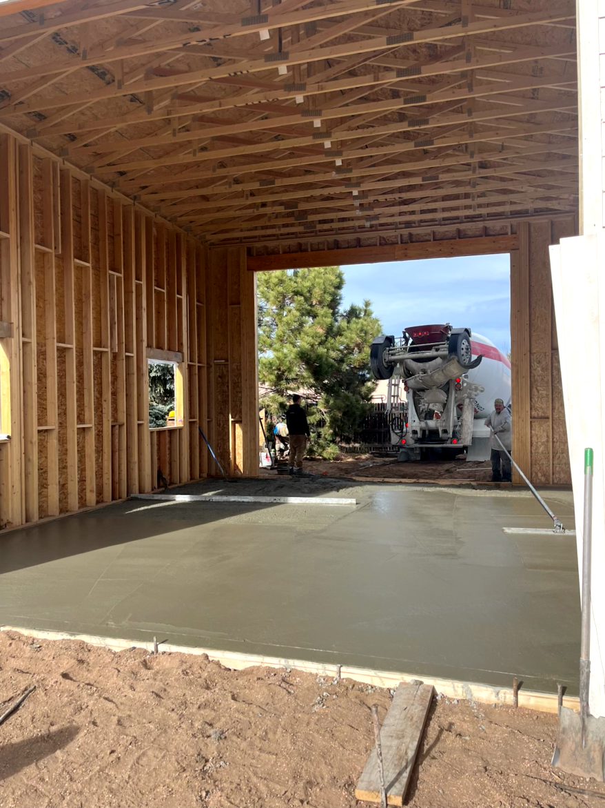 Newly poured concrete in a garage under construction; concrete truck outside.
