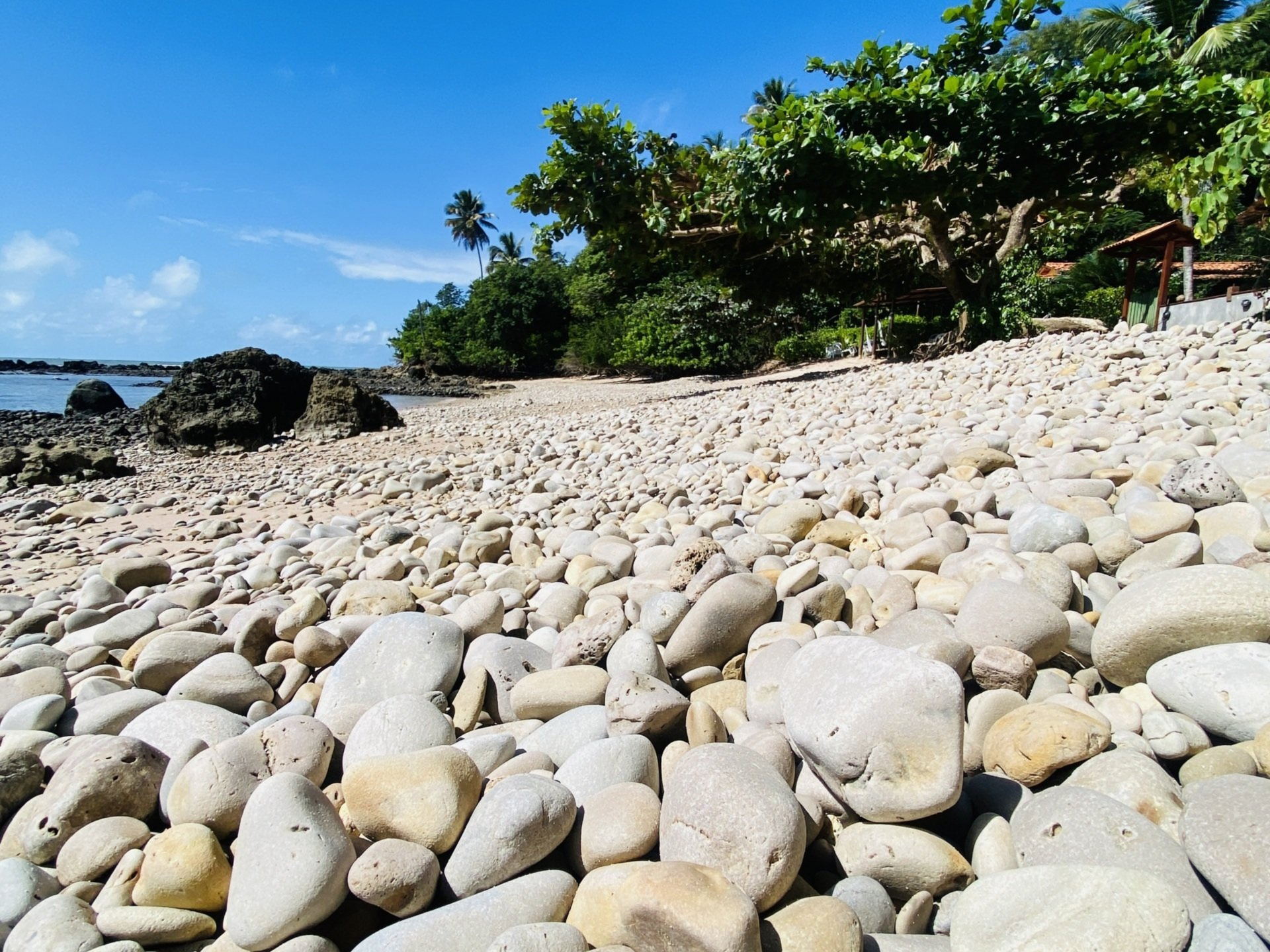 Imagem das pequenas pedras que formam a Praia das Pedrinhas, em Boipeba, Bahia.