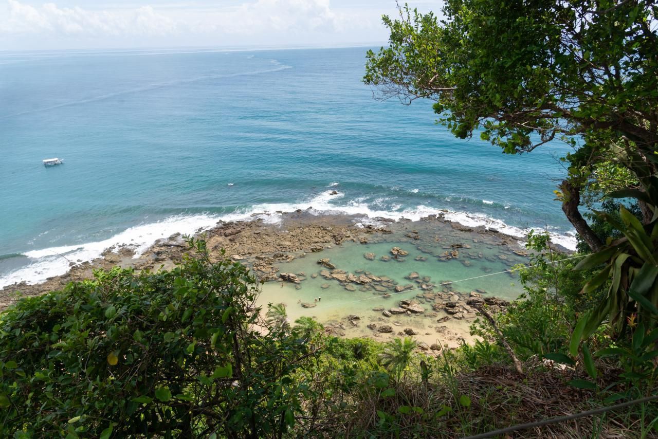 Imagem de uma trilha em Morro de São Paulo com vista para o mar em uma praia tranquila.