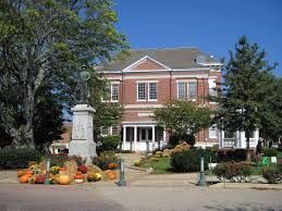 A large brick building with a statue in front of it and pumpkins in front of it.
