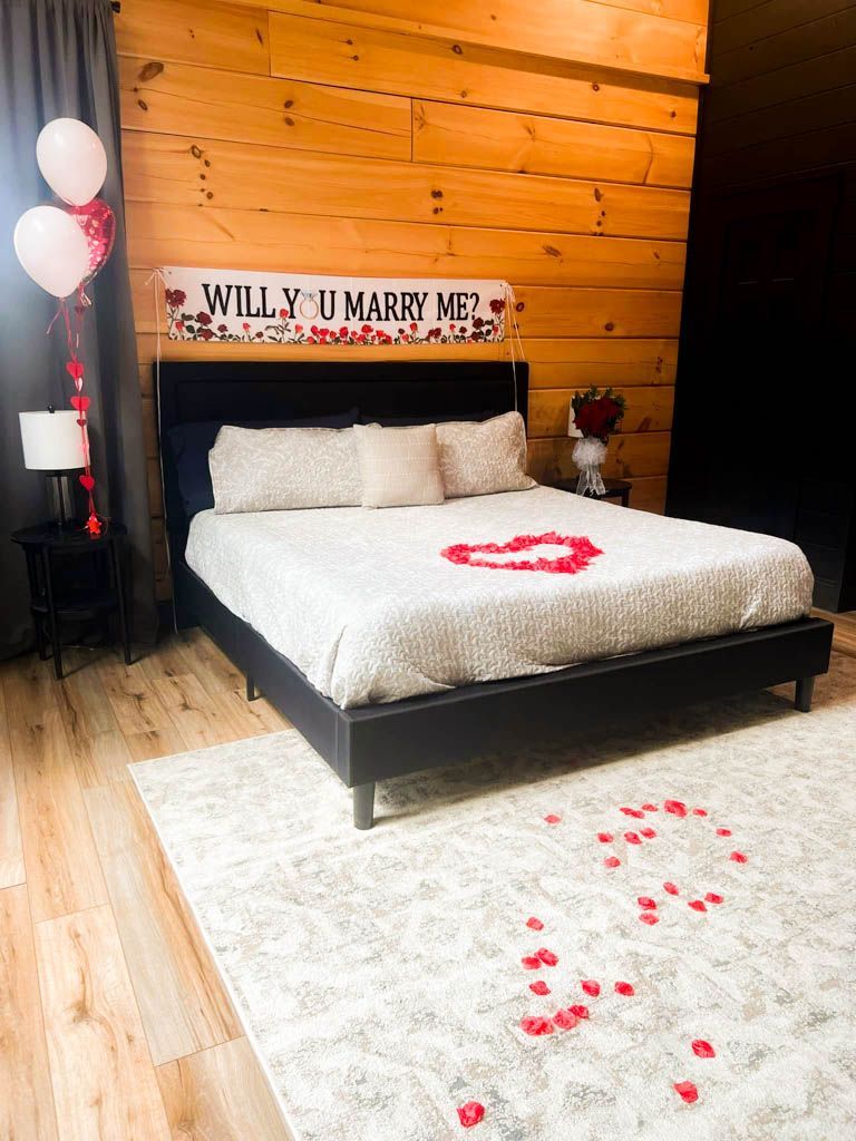 A bedroom with a bed and a sign that says `` will you marry me '' that was setup for a guest in need of concierge services.