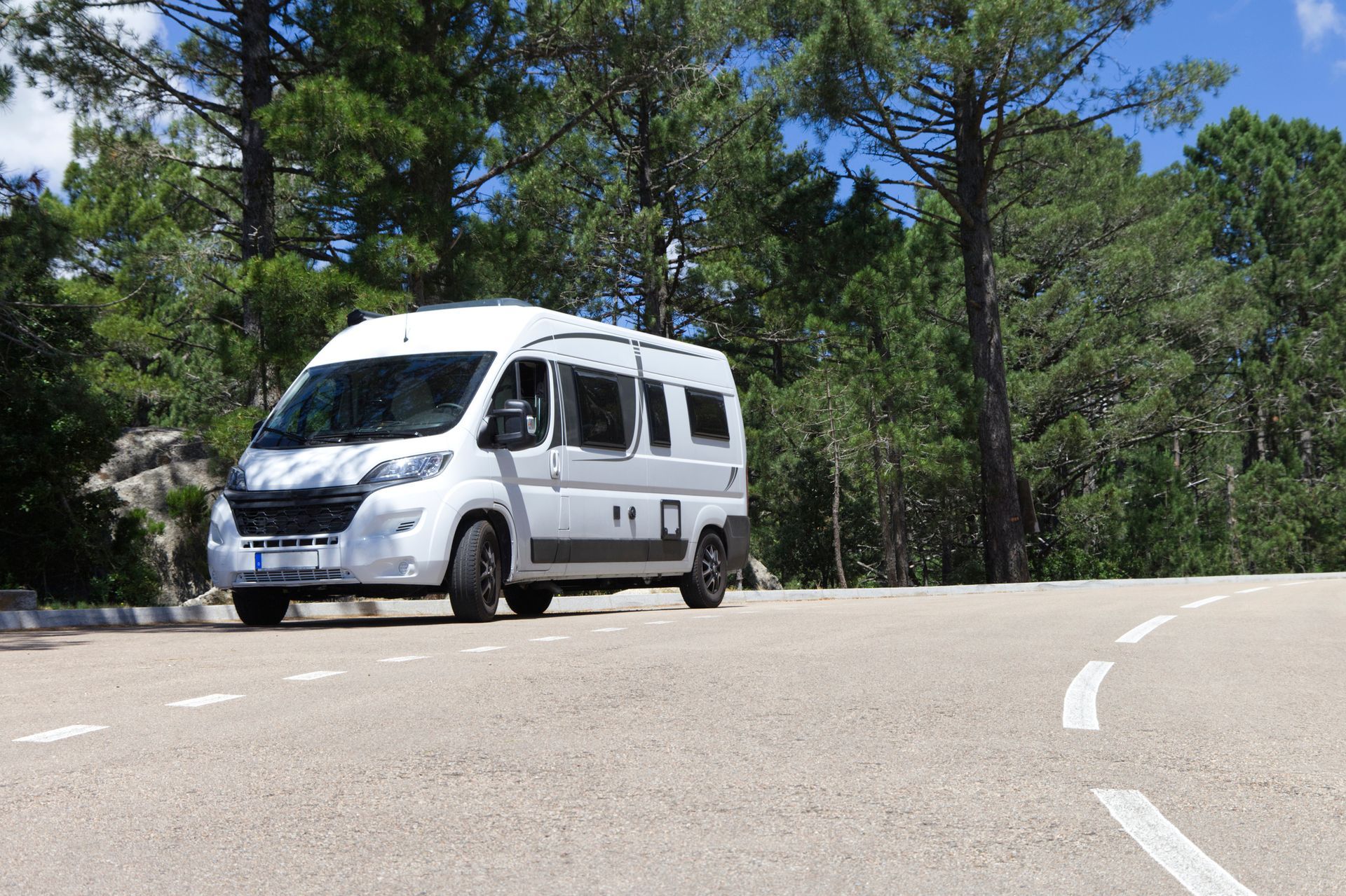A white van is driving down a curvy road.