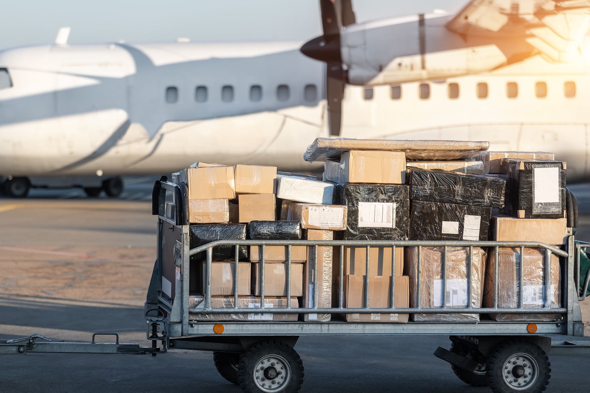 A trailer filled with boxes is parked in front of an airplane.