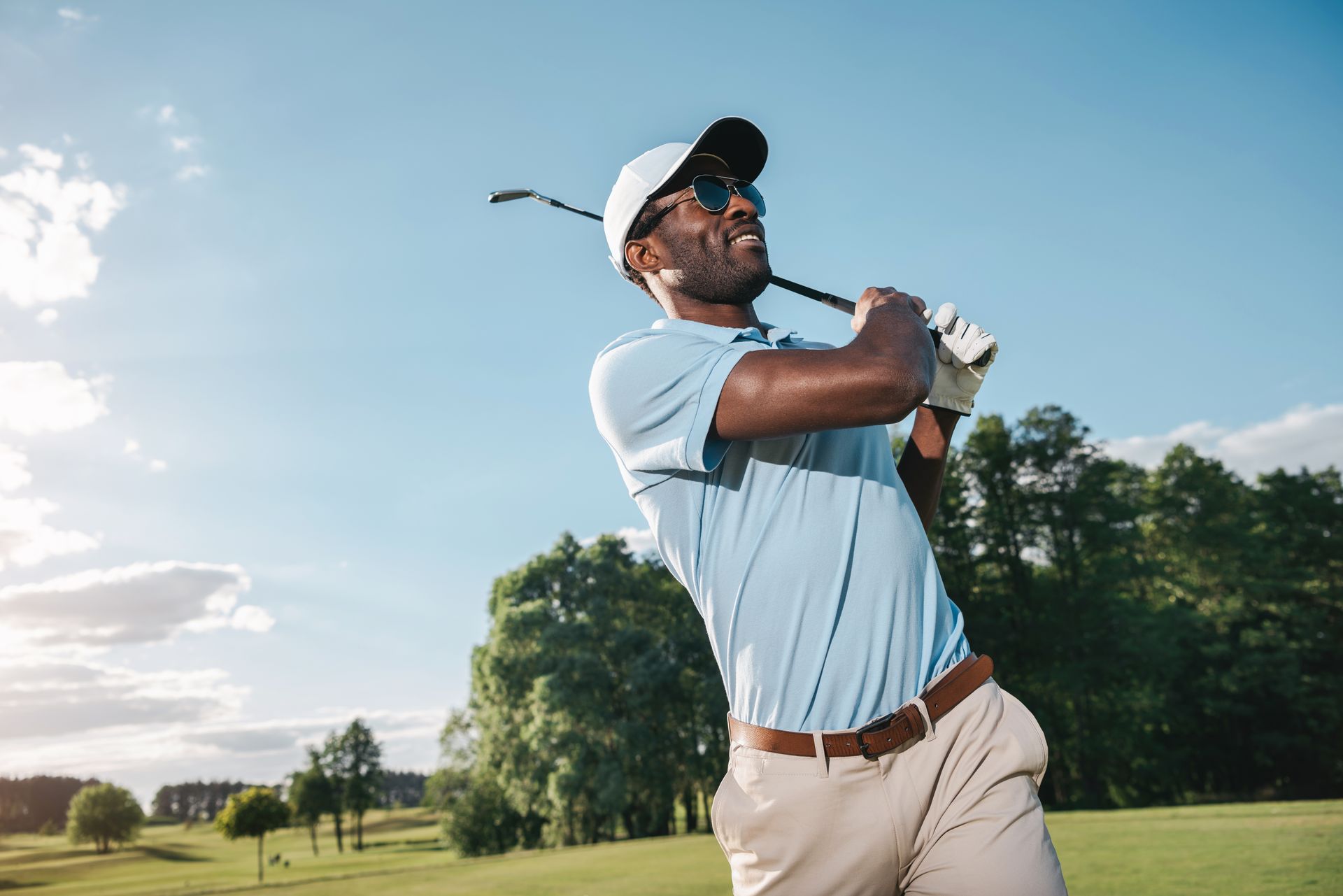 A man is swinging a golf club on a golf course.