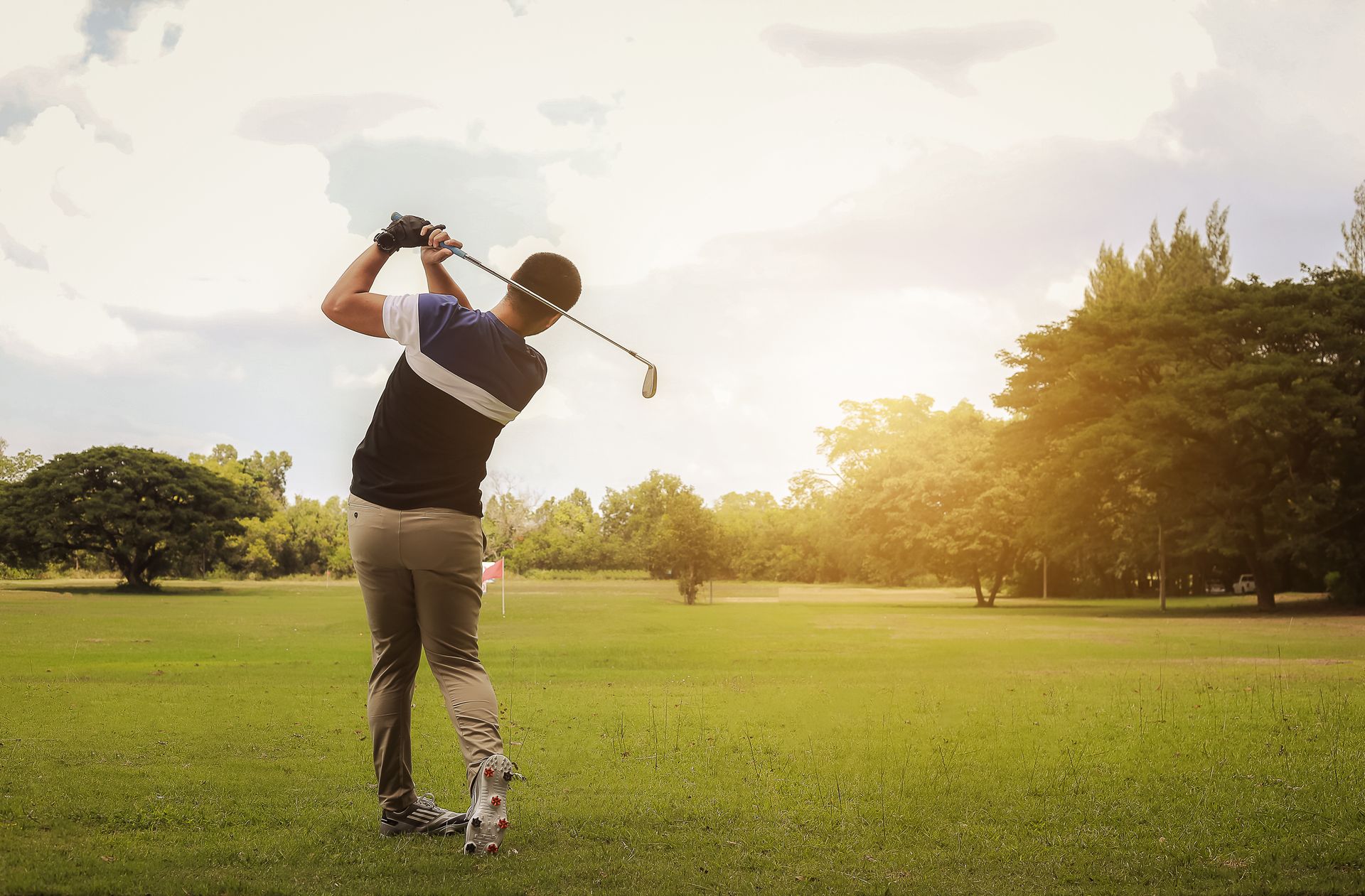A man is swinging a golf club on a golf course.