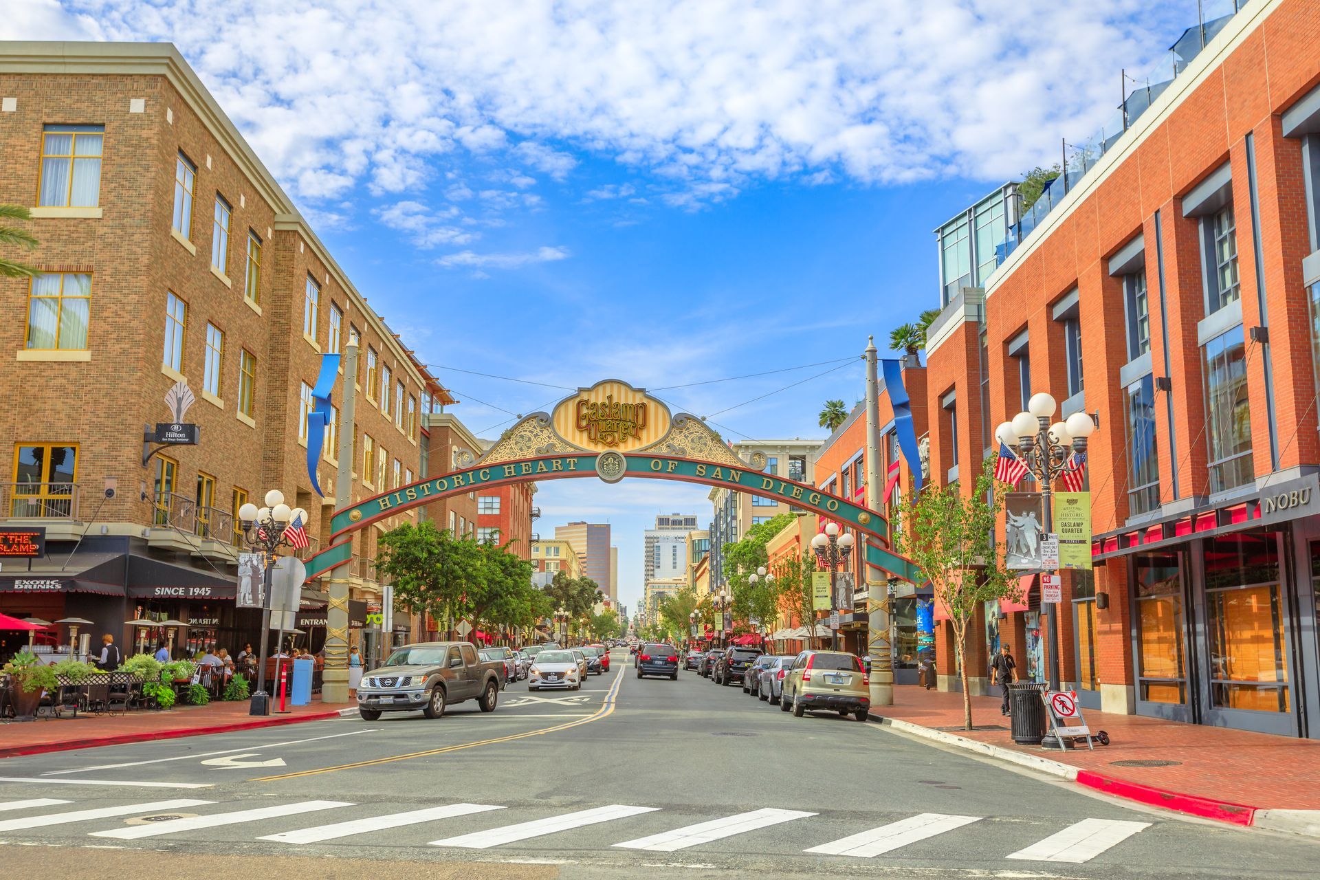 The arched entrance to San Diego’s Gaslamp Quarter, featuring historic brick buildings, street lamps, and a city street.