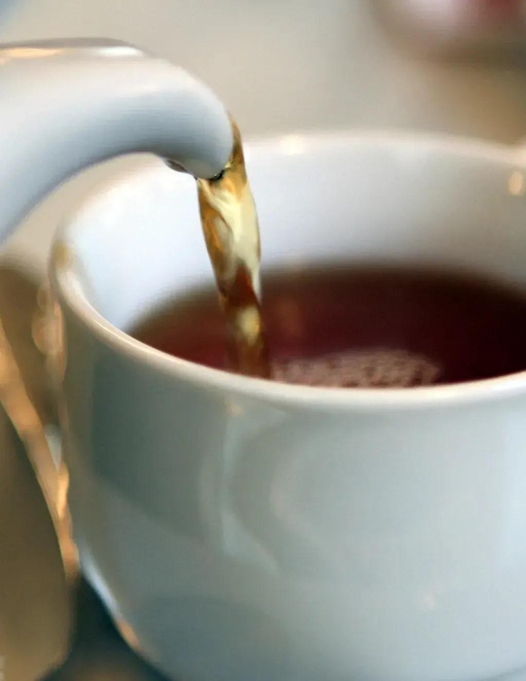 Coffee being poured into a white cup from a silver spout
