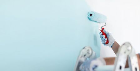 A Person is Painting a Wall with a paint Roller — Painting Services in Rockhampton, QLD