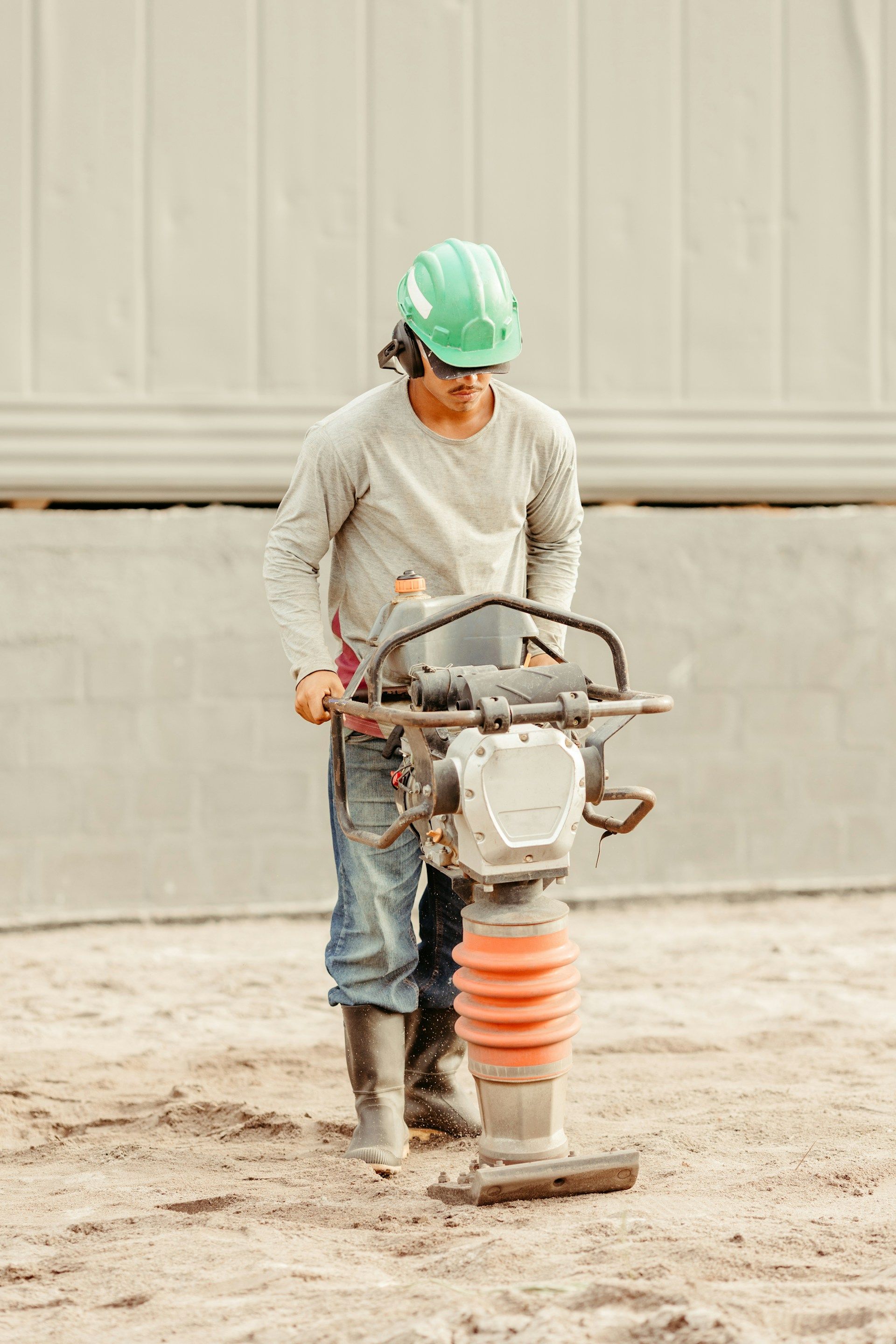 Construction worker using a jumping jack compactor on a construction site.