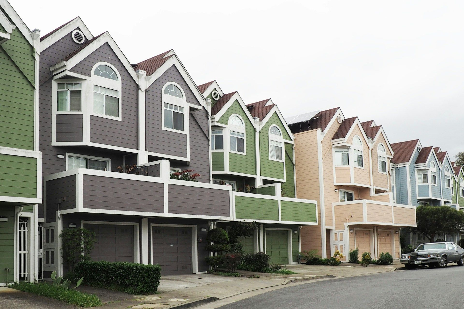 Row of colorful townhouses with garages on a curved street.