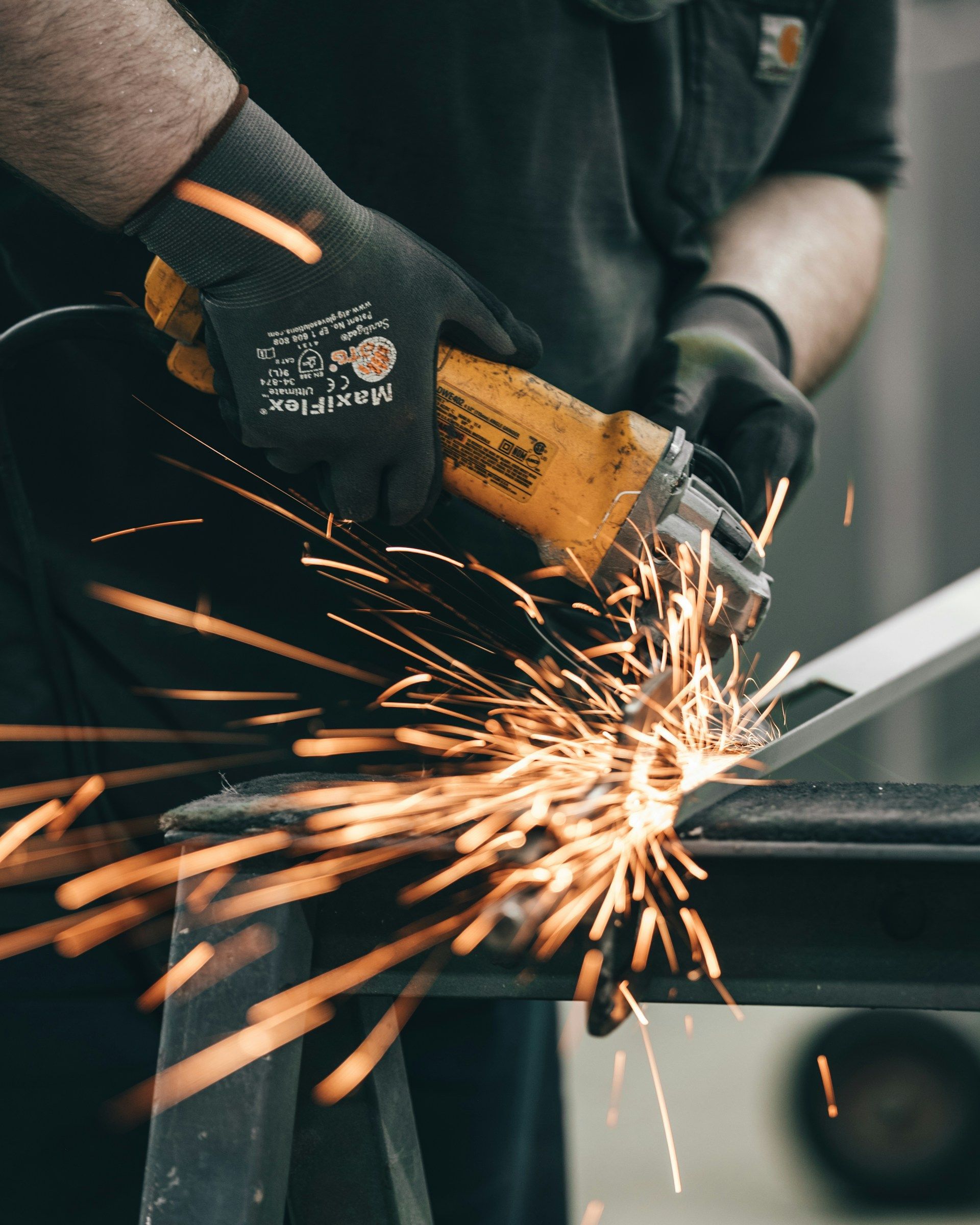 Person in dark clothes using an angle grinder, creating sparks.