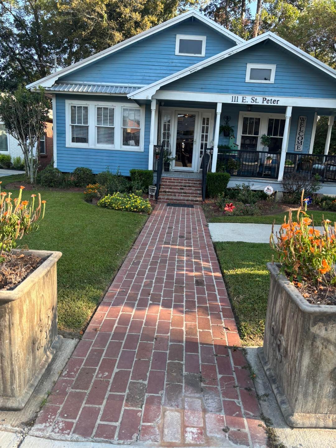 Blue house with brick walkway, porch, and landscaping.