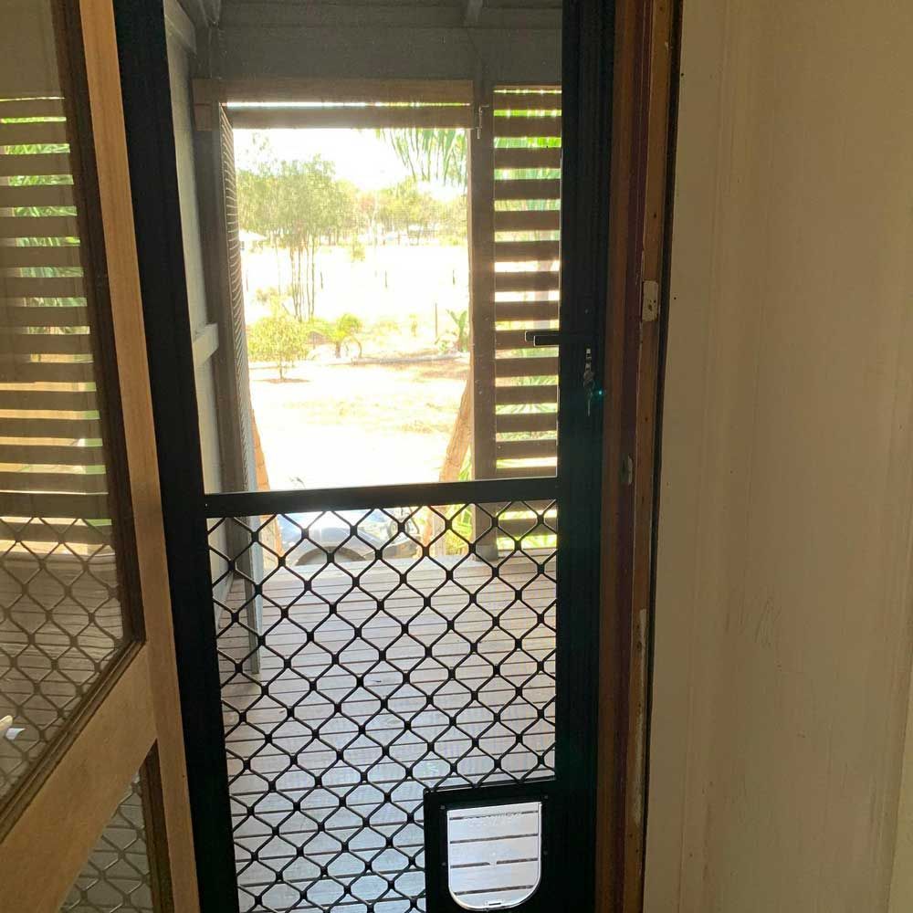 Screen Door With a Cat Door in it is Open to a Porch — Moore Park Beach Glass & Security in Bargara, QLD