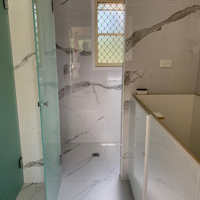 Bathroom With Marble Tiles and a Glass Shower Door — Moore Park Beach Glass & Security in Moore Park Beach, QLD