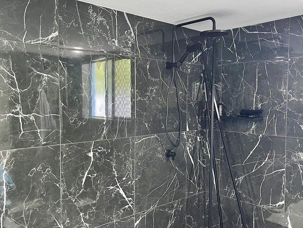 Bathroom With Black Tiles and a Black Shower Head — Moore Park Beach Glass & Security in Moore Park Beach, QLD