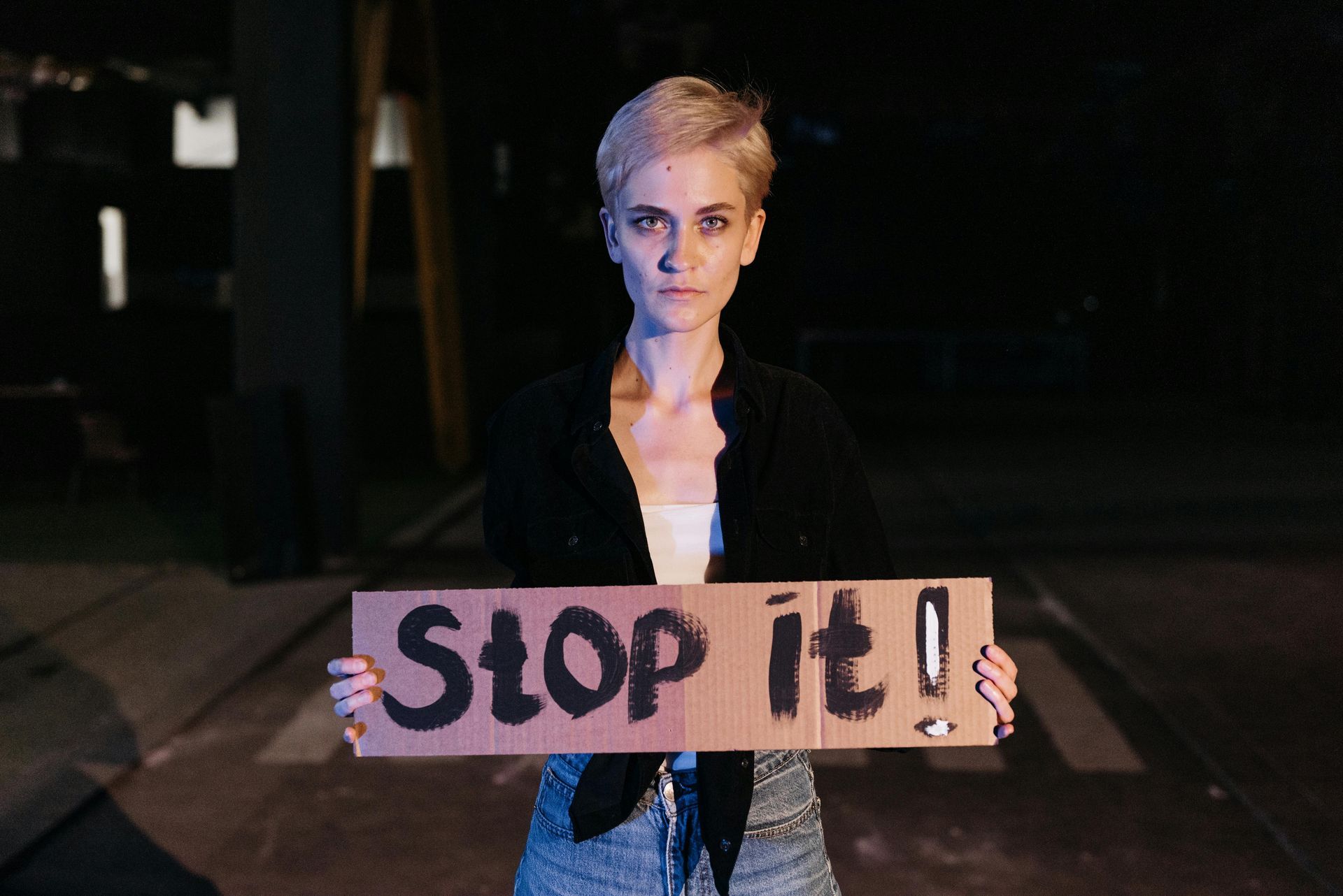 A woman is holding a sign that says `` stop it ''.