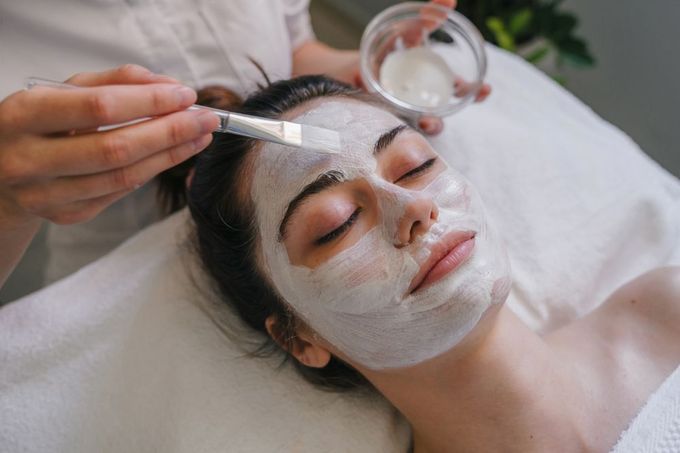 Facial treatment with a brush applying cream to a woman’s face at a spa