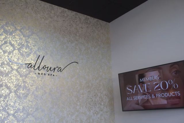 Wall with floral wallpaper, a logo, and a sign advertising 20% off all scarves and products.