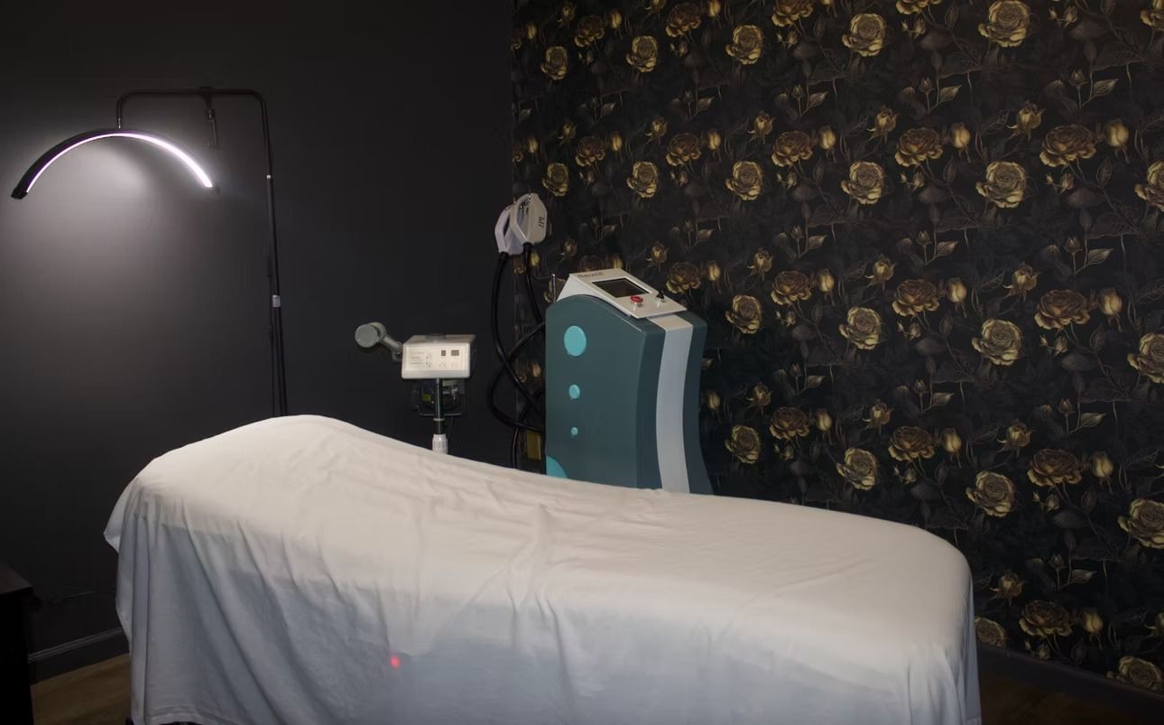 Massage room with a treatment table, wall lamp, and decorative floral wallpaper