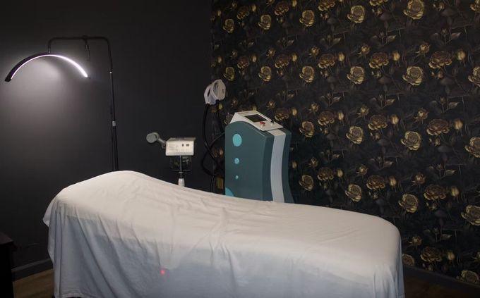 Massage room with a treatment table, wall lamp, and decorative floral wallpaper