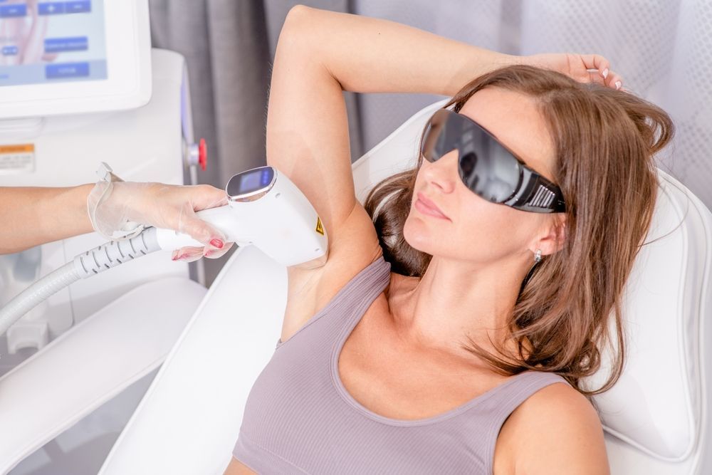 Woman receiving underarm laser treatment while wearing protective goggles in a clinic