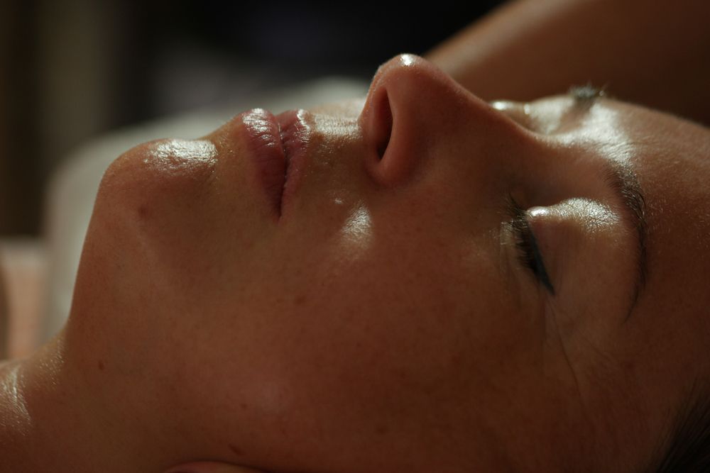 Close-up of a person lying on their back with eyes closed, face lit softly in warm light.