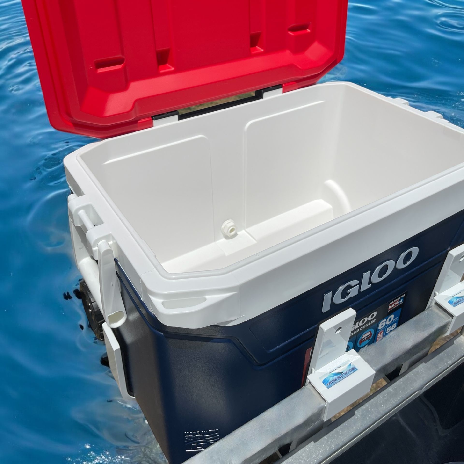 Pontoon boat cooler mounted on metal legs, red lid and blue Igloo body.