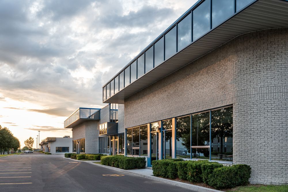 A large brick building with a lot of windows and a parking lot in front of it.