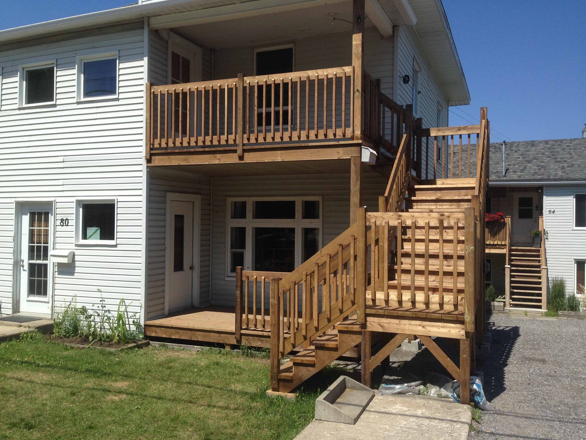 Maison à deux étages avec terrasses en bois et escaliers extérieurs par une journée ensoleillée