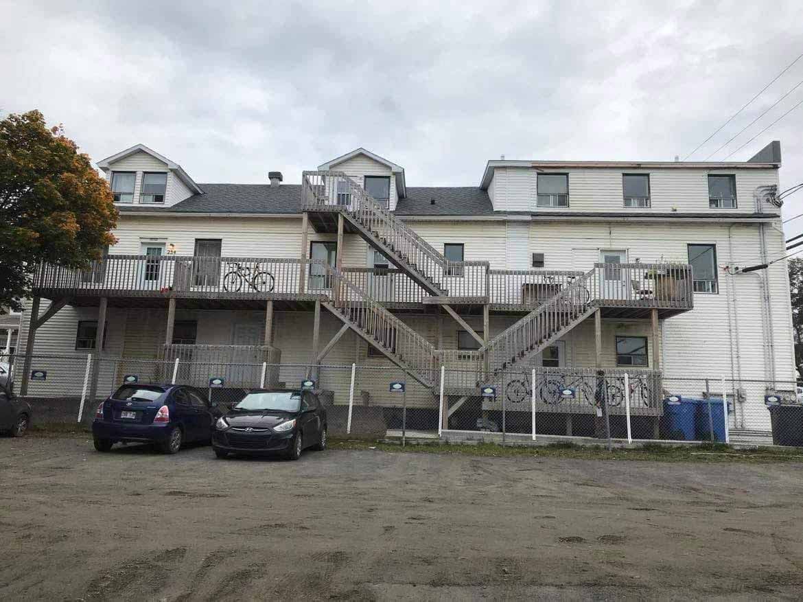Immeuble d'appartements délabré avec escaliers extérieurs et voitures garées devant