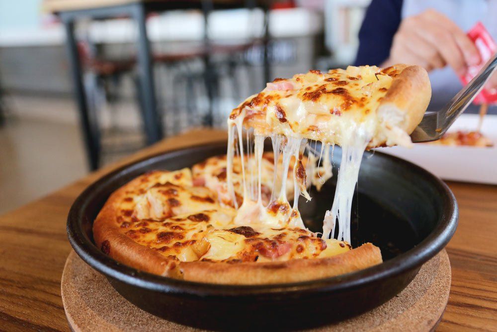 A person is taking a slice of pizza out of a pan.