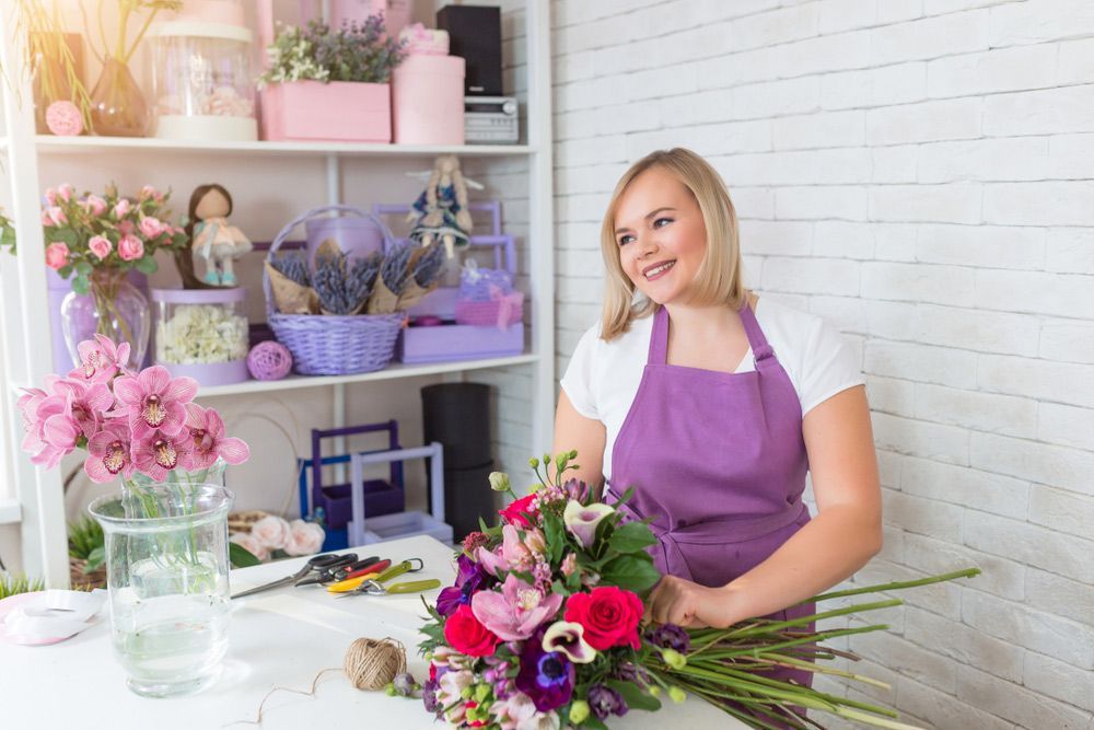 A Woman in A Purple Apron Is Making a Bouquet of Flowers in A Flower Shop — Pick-A-Bunch Florists & Gifts In Sarina, QLD