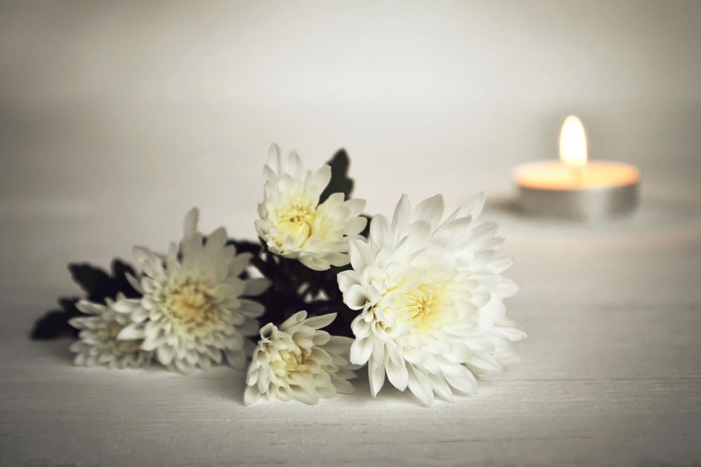 A Bouquet of White Flowers and A Lit Candle on A Table — Pick-A-Bunch Florists & Gifts In Alligator Creek, QLD
