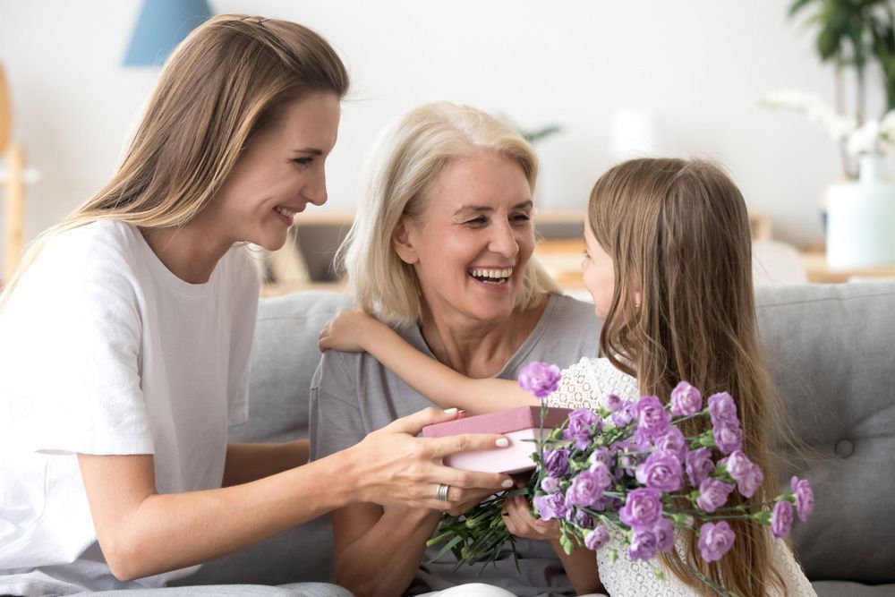 A Little Girl Is Giving an Older Woman a Gift and Flowers — Pick-A-Bunch Florists & Gifts In Sarina, QLD