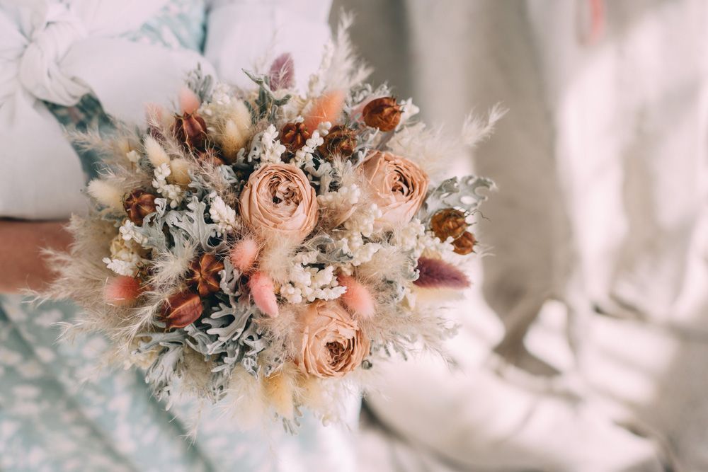 A Woman Is Holding a Bouquet of Dried Flowers in Her Hands — Pick-A-Bunch Florists & Gifts In Sarina, QLD