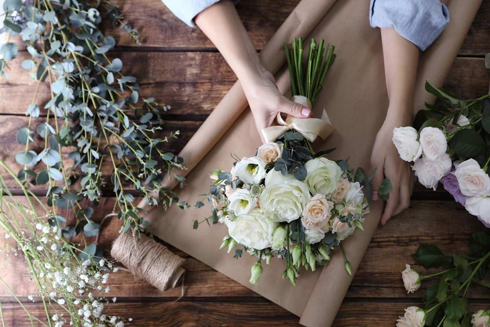 A Person Is Wrapping a Bouquet of Flowers in Brown Paper — Pick-A-Bunch Florists & Gifts In Sarina, QLD