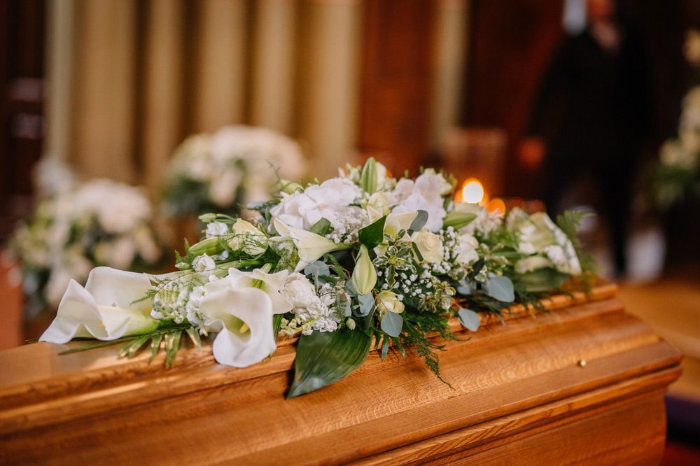 A Wooden Coffin with Flowers on It in A Funeral Home — Pick-A-Bunch Florists & Gifts In Sarina, QLD