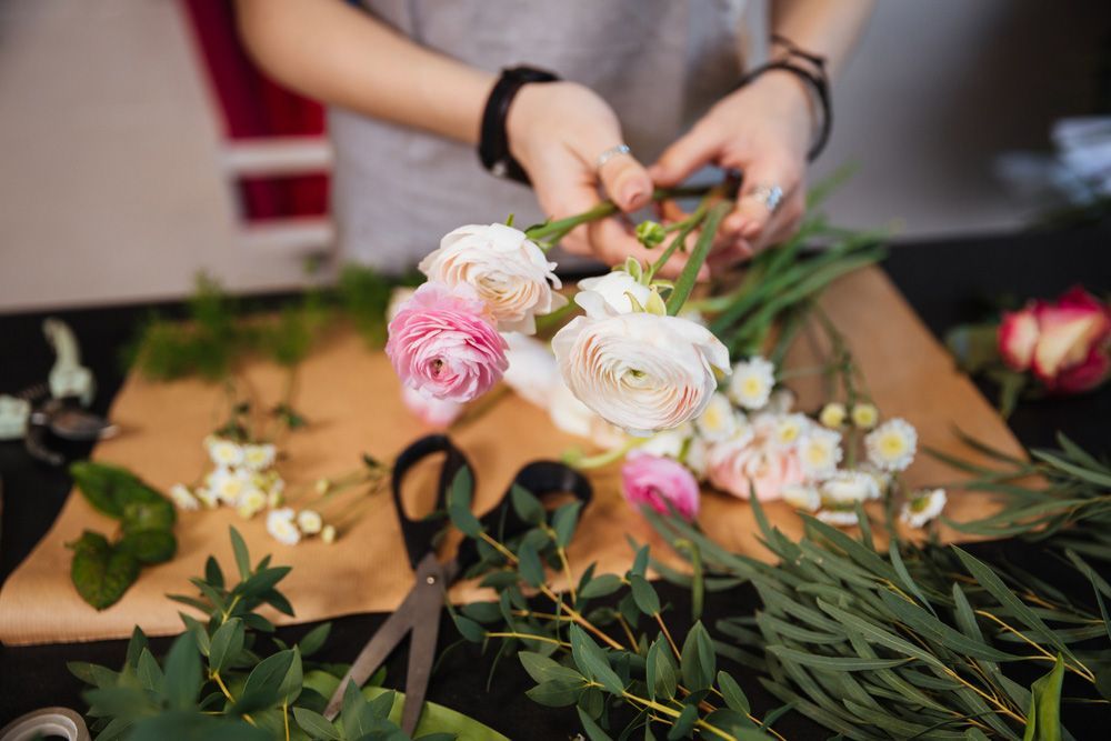 A Woman Is Making a Bouquet of Flowers with Scissors — Pick-A-Bunch Florists & Gifts In Armstrong Beach, QLD