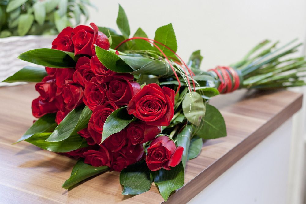 A Bouquet of Red Roses Is Sitting on A Wooden Table — Pick-A-Bunch Florists & Gifts In Hay Point, QLD