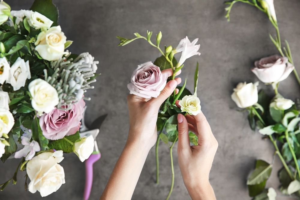 A Woman Is Making a Bouquet of Flowers with Scissors — Pick-A-Bunch Florists & Gifts In Armstrong Beach, QLD