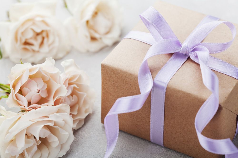 A Gift Box with A Purple Ribbon and Roses in The Background — Pick-A-Bunch Florists & Gifts In Sarina, QLD