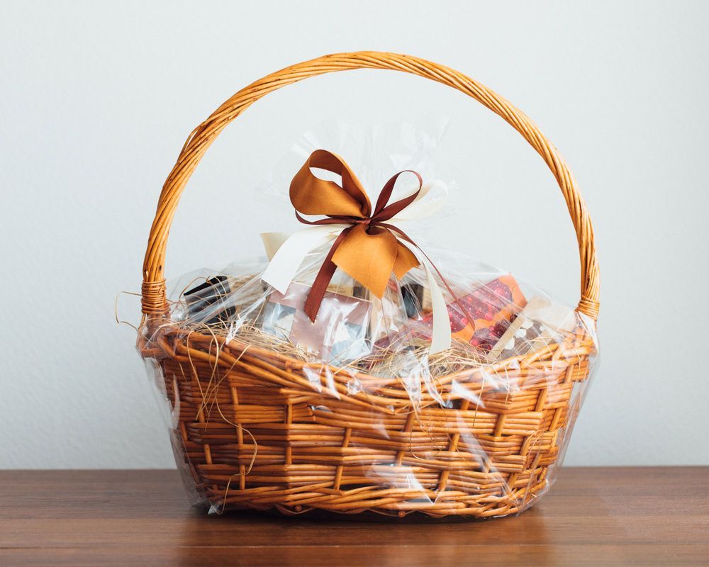 A Wicker Basket with A Bow Is Sitting on A Wooden Table — Pick-A-Bunch Florists & Gifts In Hay Point, QLD