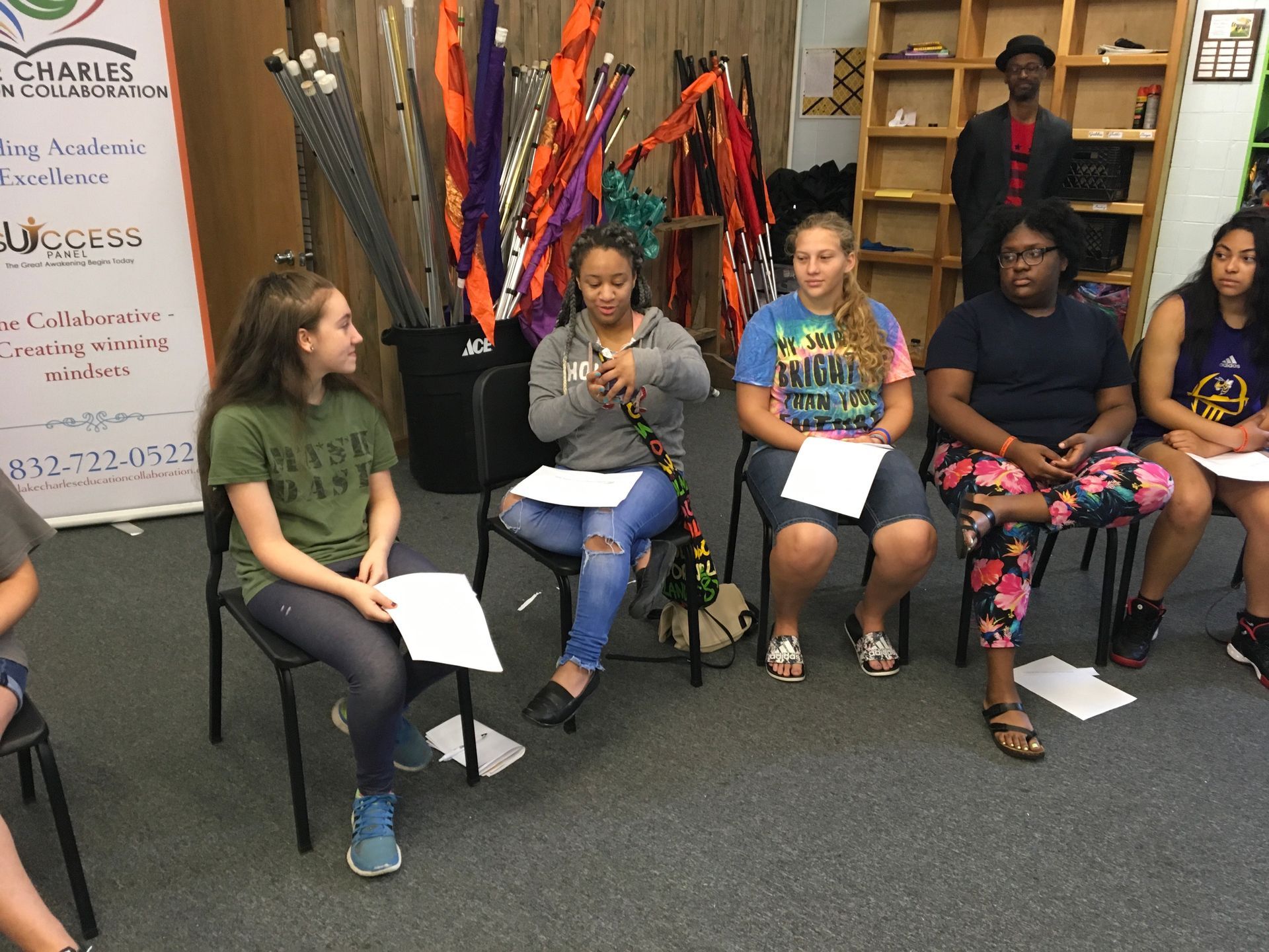 Group of people seated, holding papers, and participating in a discussion.
