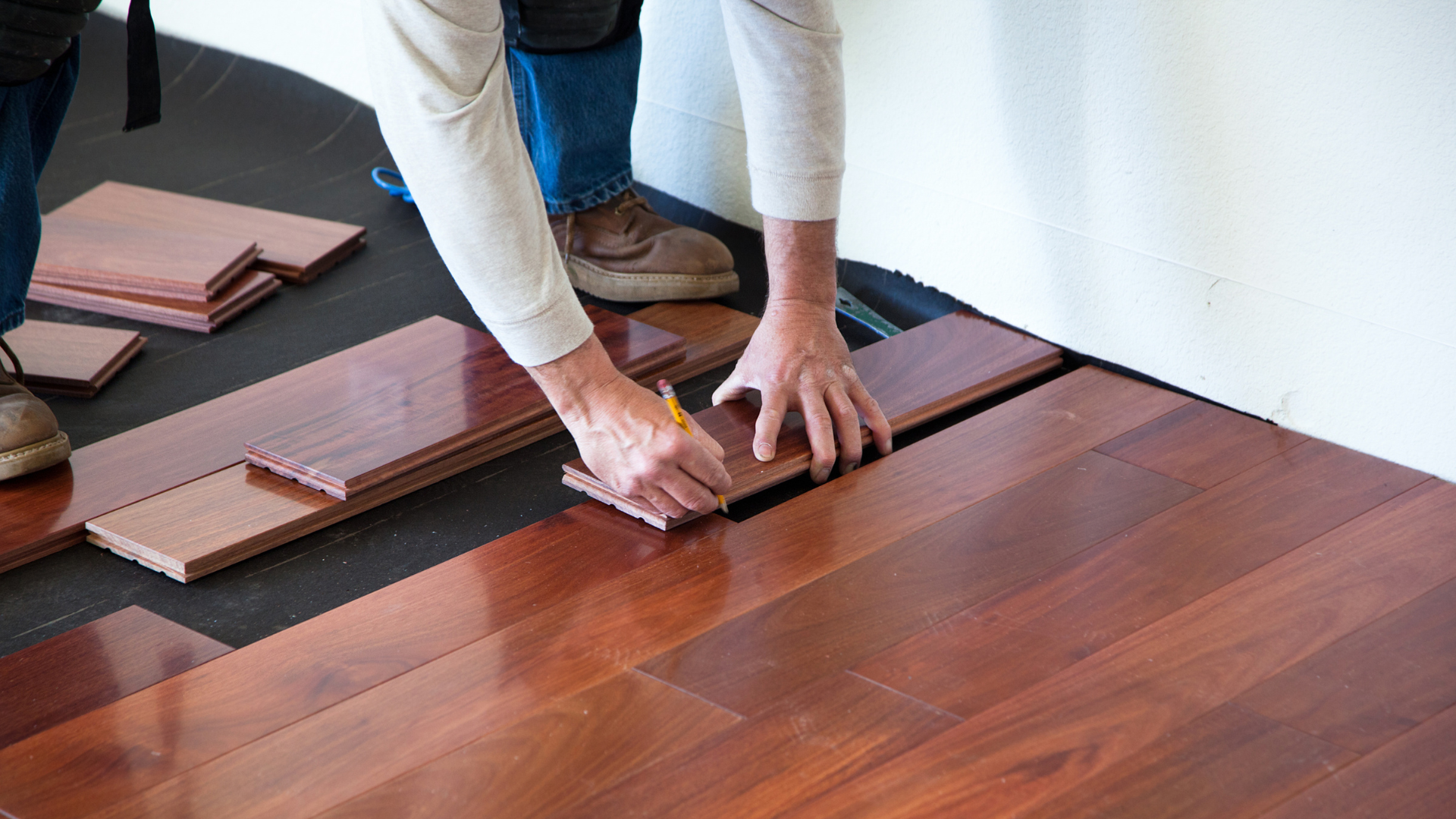 Professional hardwood flooring installation services with expert installers preparing and installing quality wood floors in a residential home