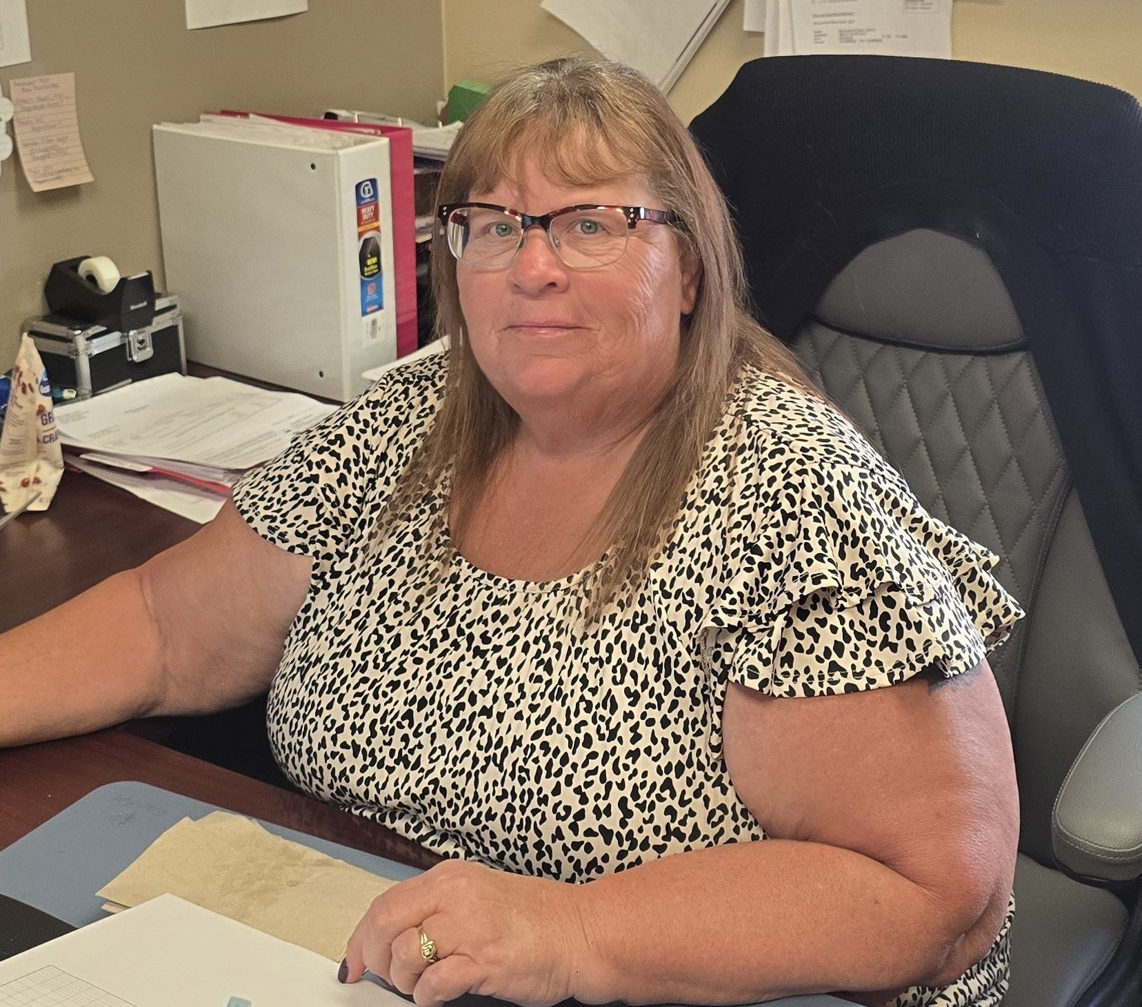A woman wearing glasses is sitting at a desk