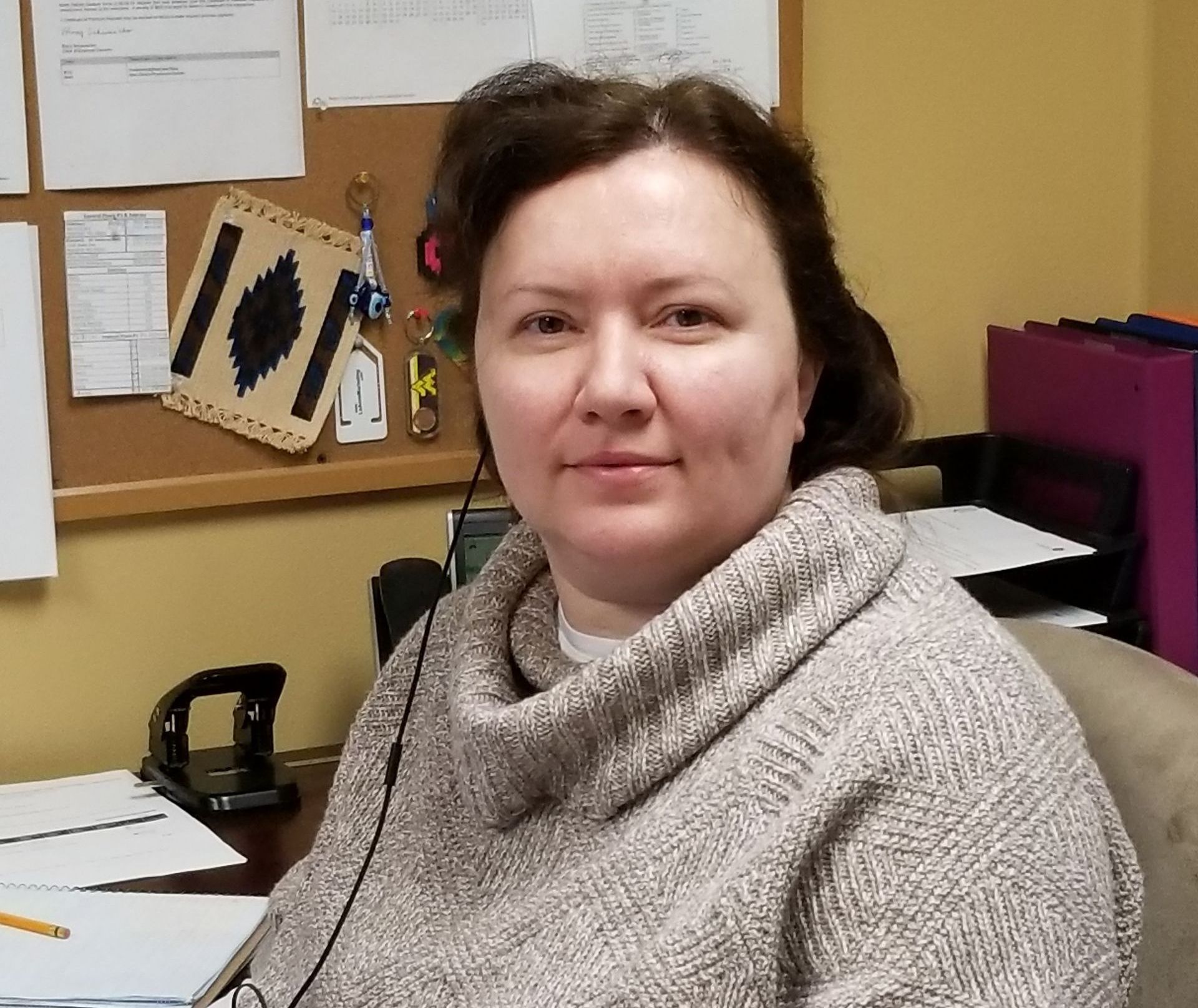 A woman in a sweater is sitting at a desk