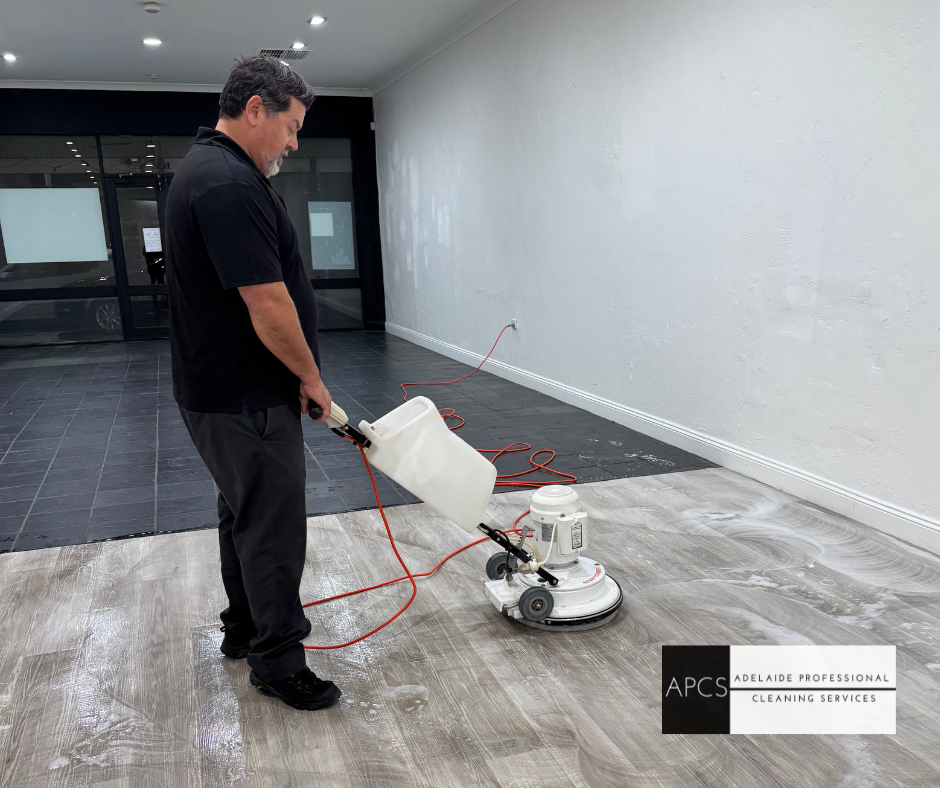 Man using floor cleaner, emptying solution into machine, in a commercial space.
