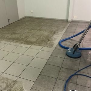 Tile floor being cleaned with a rotary scrubber, showing the difference between clean and dirty sections.