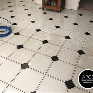 White and black tiled floor with a glossy finish.  A blue hose and wooden cabinet are also present.